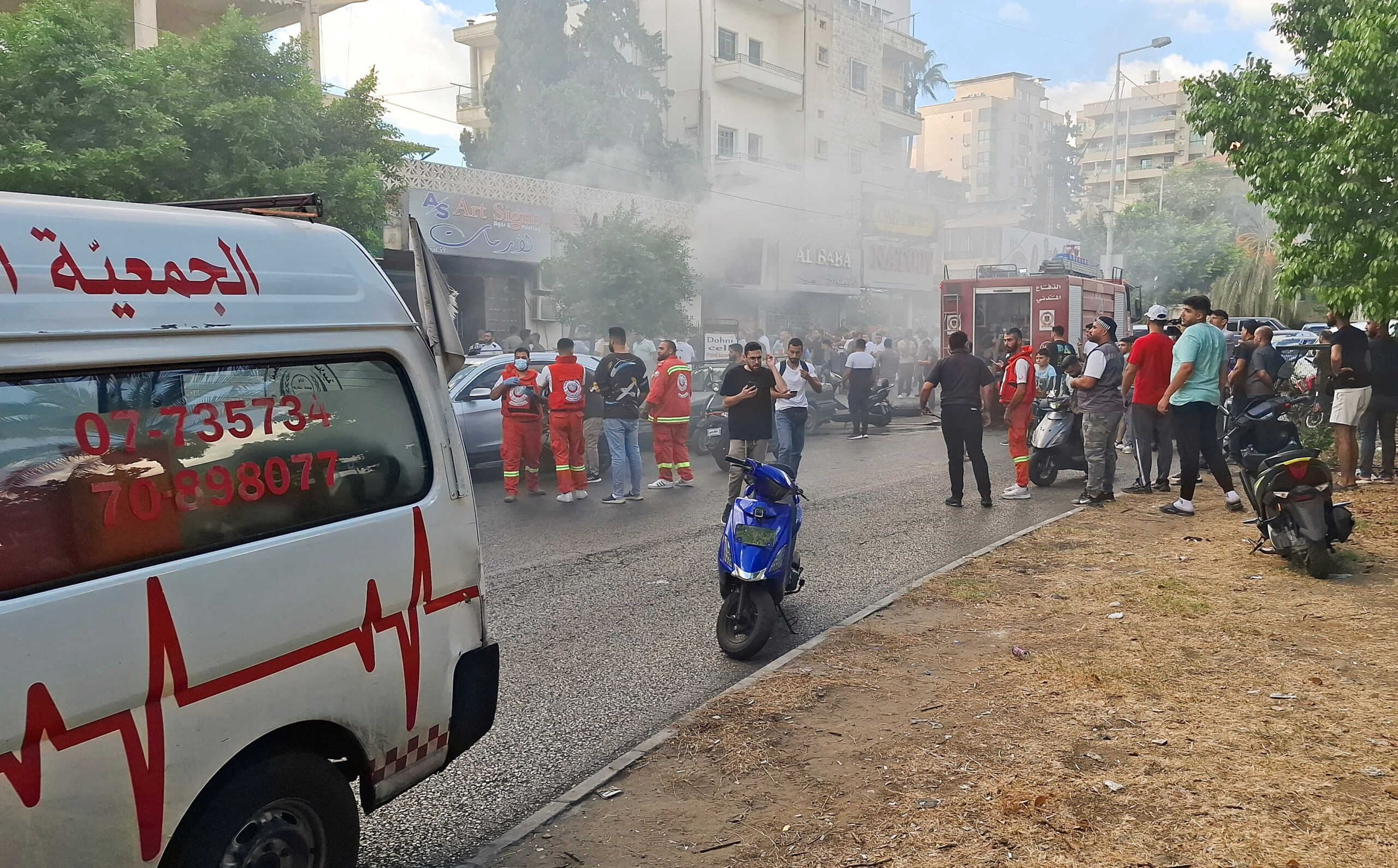 Smoke rises from a mobile shop as civil defence members gather in Sidon, Lebanon September 18, 2024. REUTERS