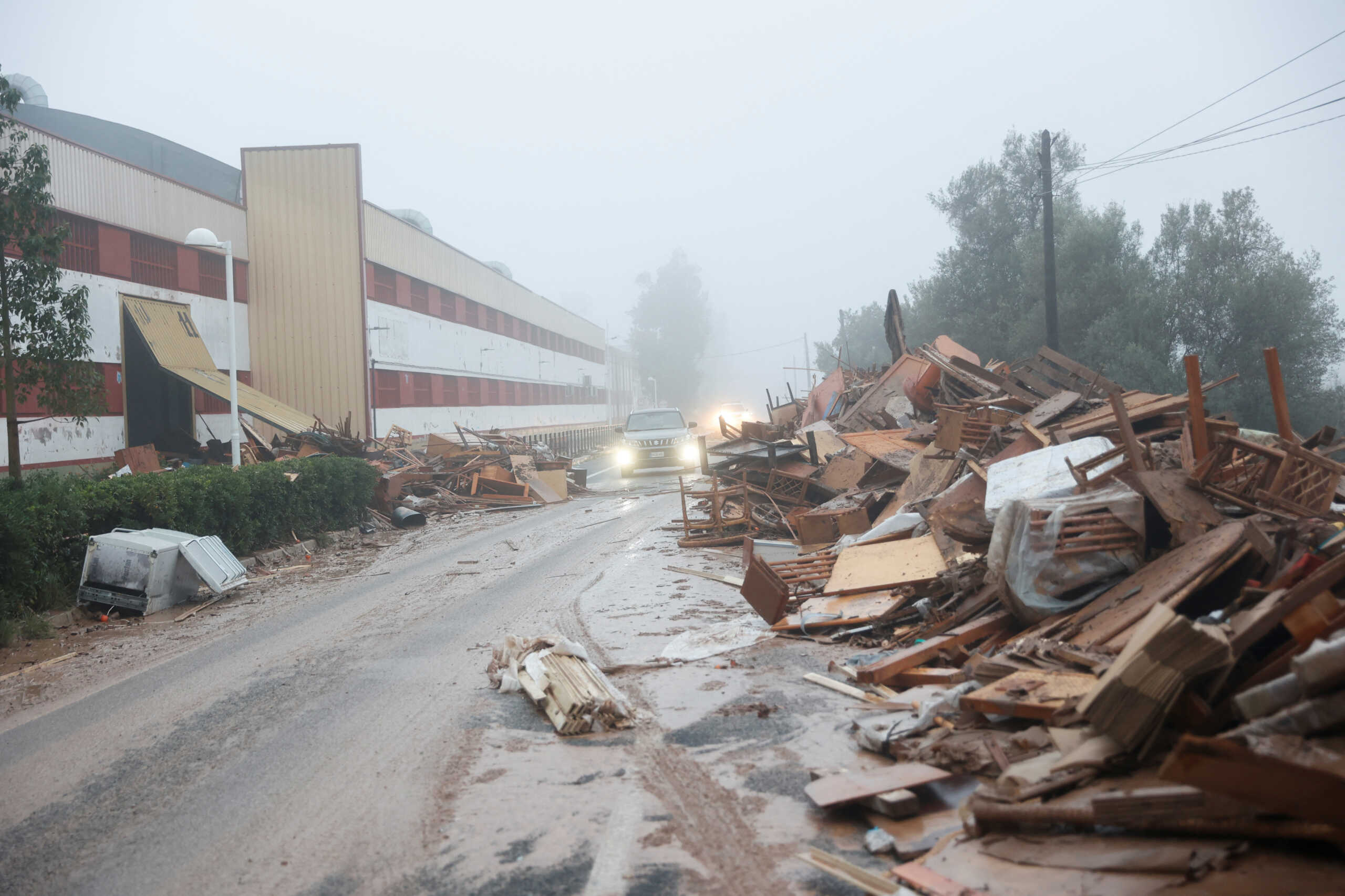 A car drives past damaged items from a furniture factory affected by torrential rains that caused flooding in La Alcudia, Valencia region, Spain, October 30, 2024. REUTERS