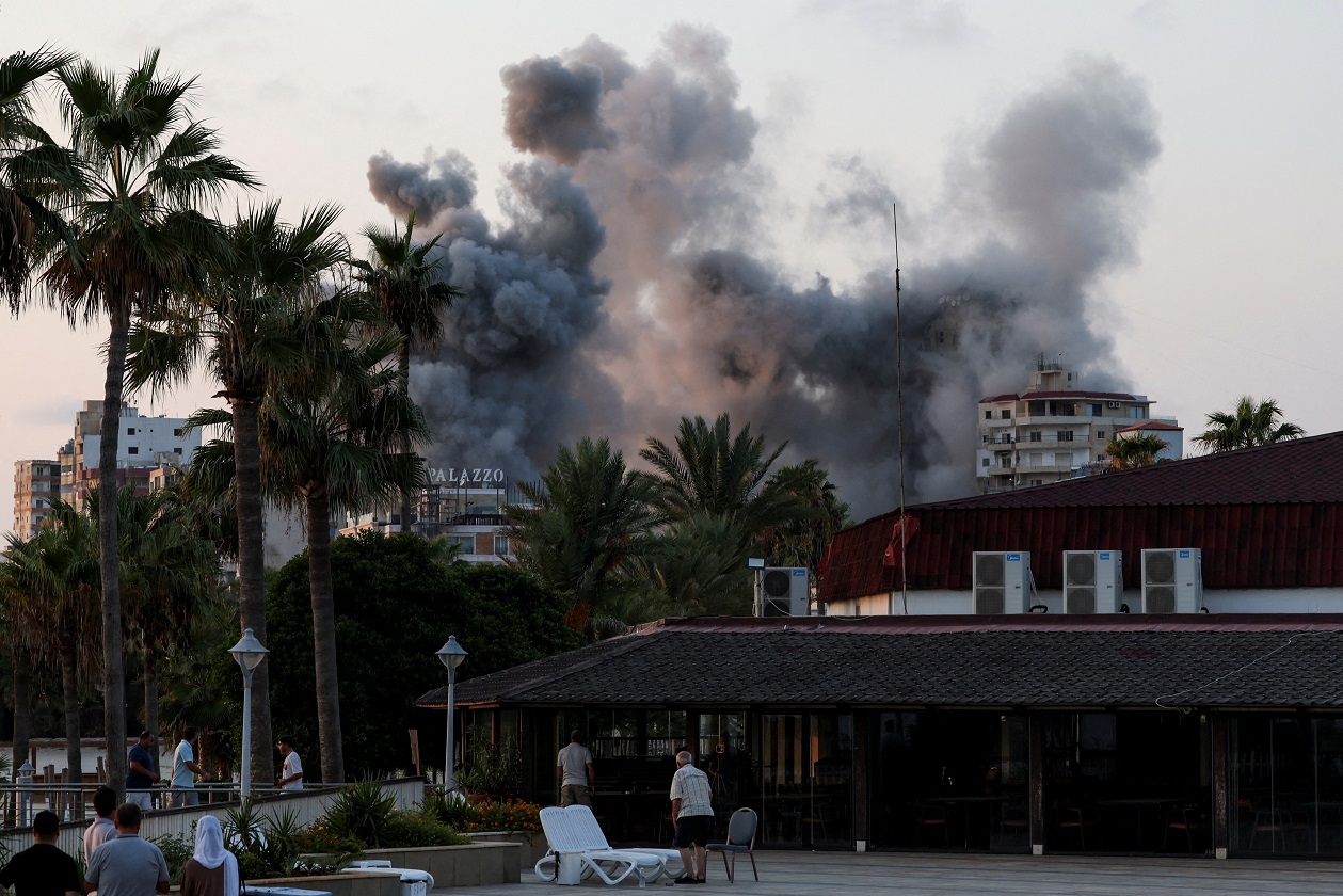 People look on, as smoke billows amid the ongoing hostilities between Hezbollah and Israeli forces, in Tyre, southern Lebanon, October 7, 2024. REUTERS