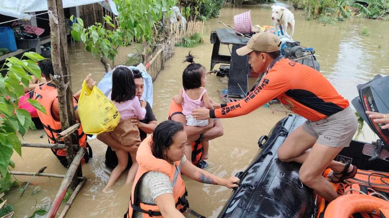 Philippine Coast Guard personnel rescue residents after flood waters rose from heavy rains brought by Tropical Storm Trami, in Bicol, Philippines, October 23, 2024. PHILIPPINE COAST GUARD