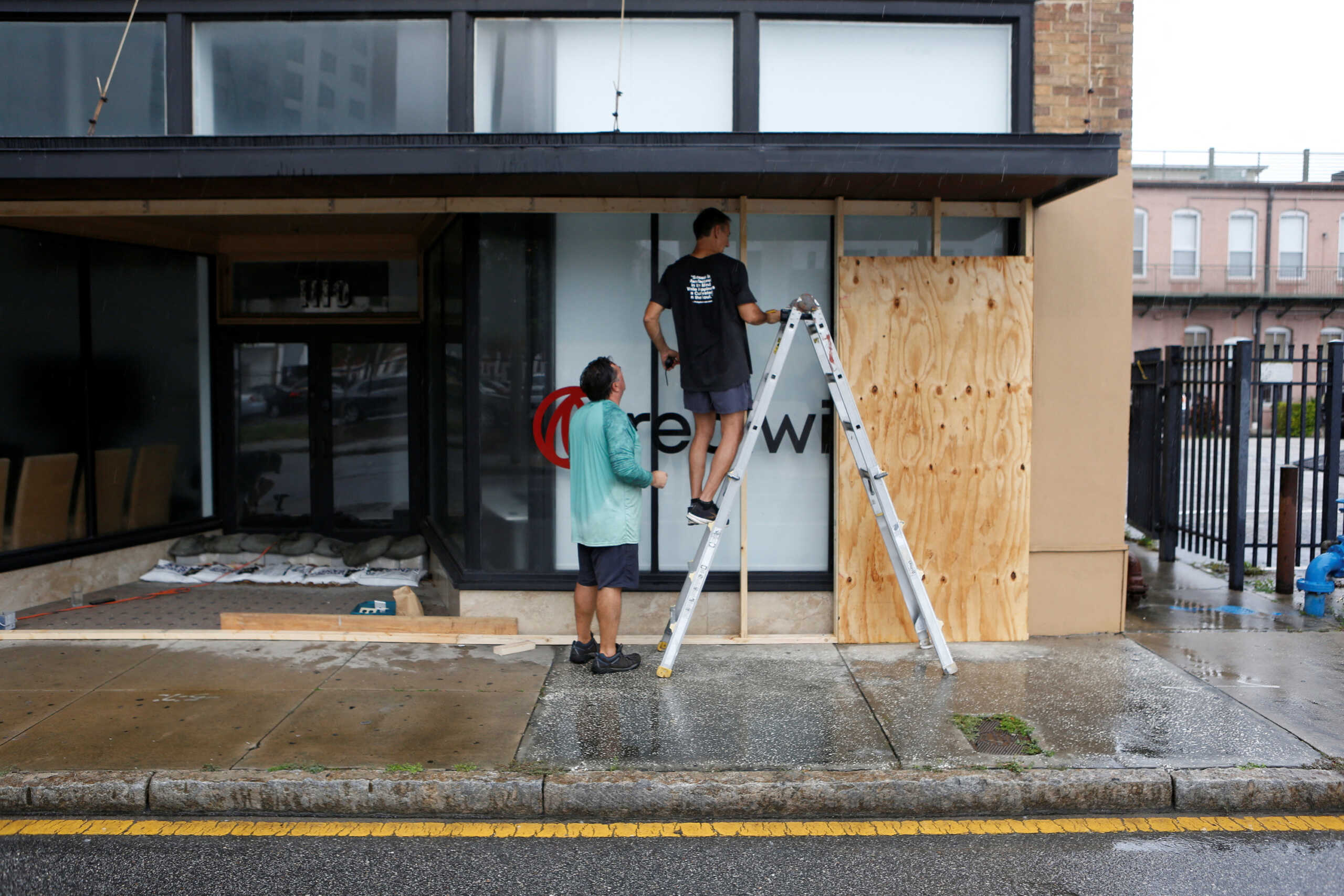 Jeff Hicks (L) gets help from his friend Chris Ahern with boarding up his business ahead of the arrival of Hurricane Milton in downtown Tampa, Florida., U.S., October 8, 2024. REUTERS