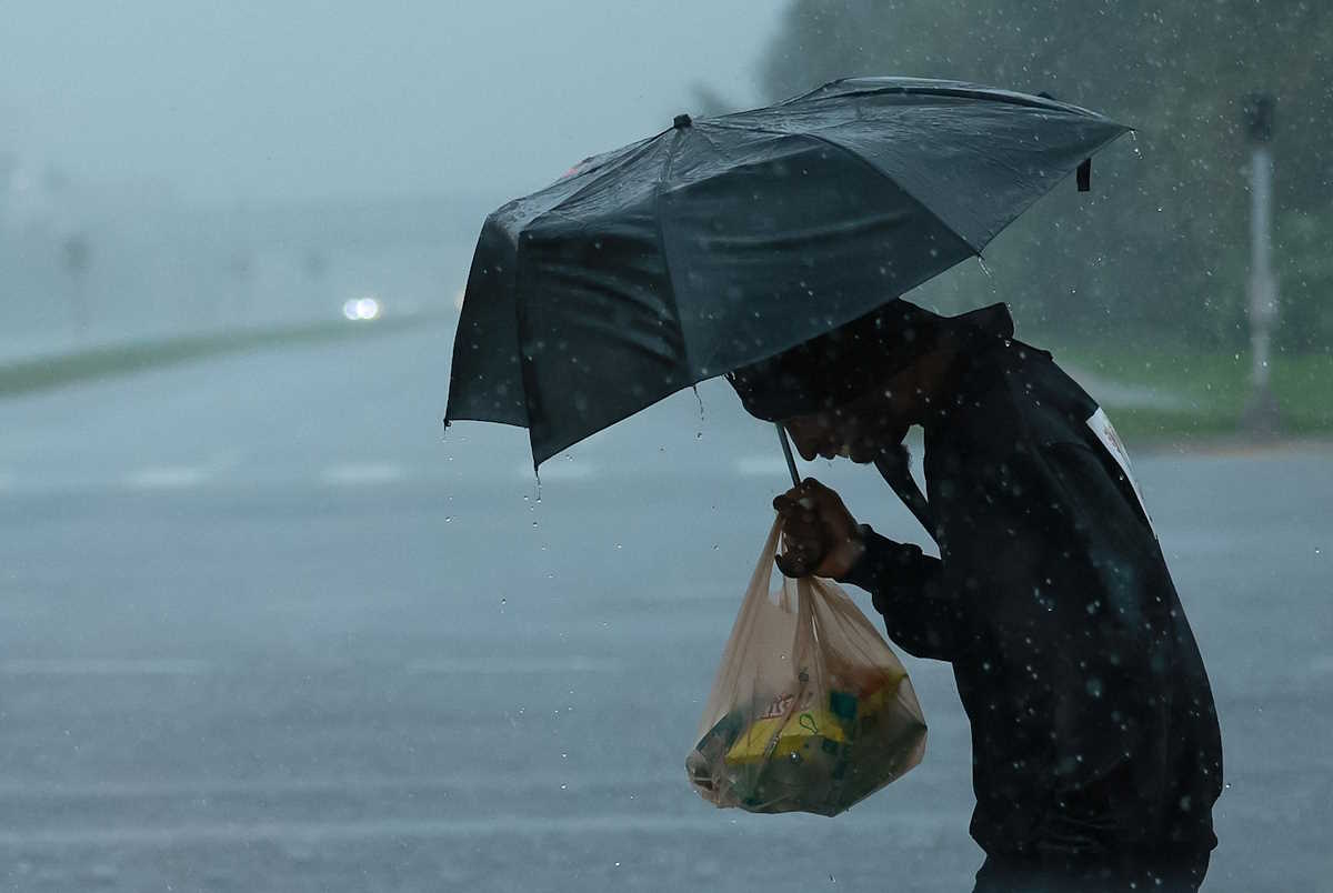 A person holds an umbrella as Hurricane Milton approaches, in Orlando, Florida, U.S., October 9, 2024.  REUTERS