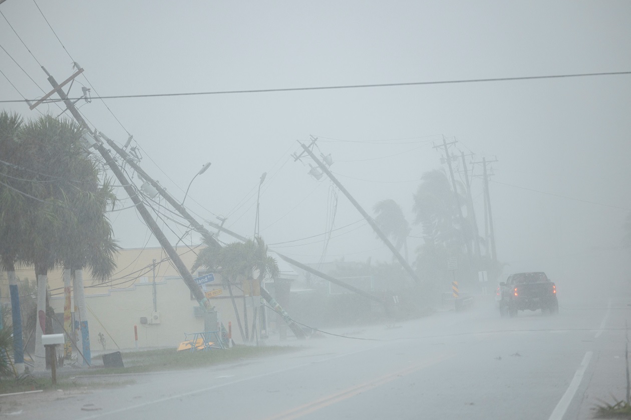 A motorist drives past broken utility poles downed by strong wind gusts as Hurricane Milton approaches Fort Myers, Florida, U.S. October 9, 2024. REUTERS