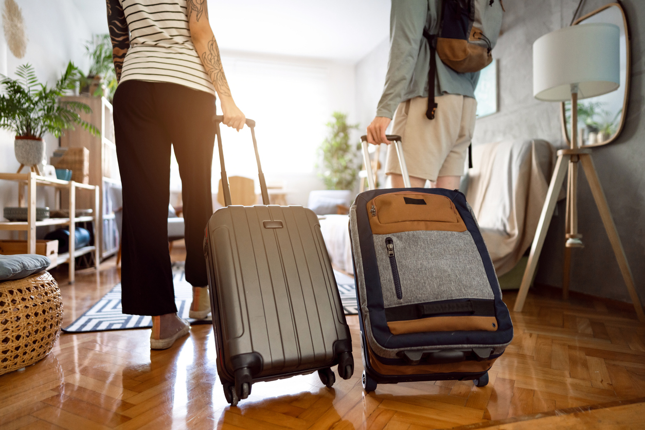 Rear-view of an unrecognizable couple arriving at the accommodation with their suitcases