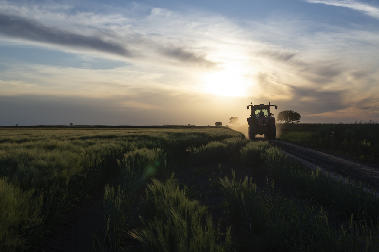 Tractor on a dirt country road at sunset