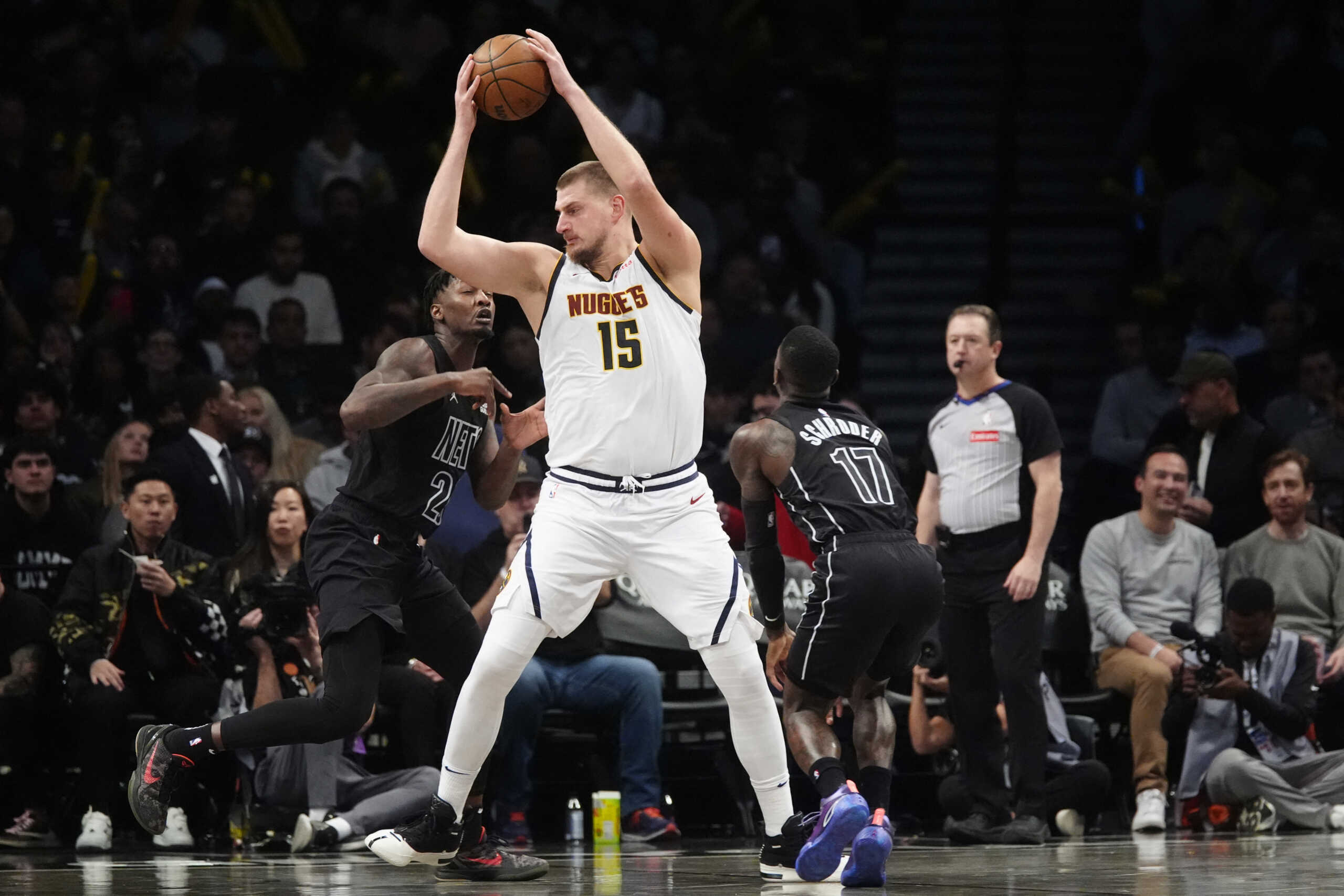 Oct 29, 2024; Brooklyn, New York, USA; Denver Nuggets center Nikola Jokic (15) looks to make a move on Brooklyn Nets small forward Cameron Johnson (2) and Brooklyn Nets point guard Dennis Schroder (17) during the second half at Barclays Center. Mandatory Credit: Gregory Fisher-Imagn Images