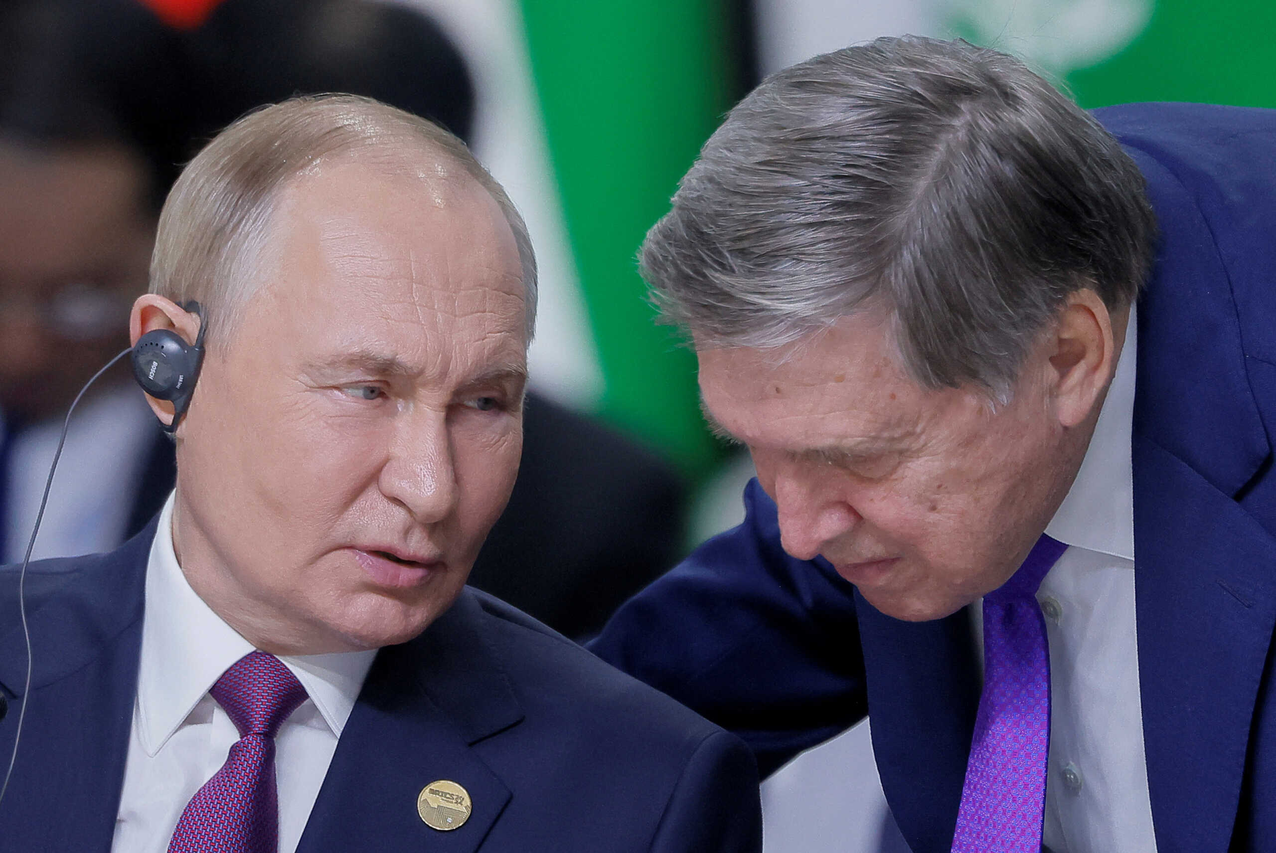 Russian President Vladimir Putin speaks with his aide Yuri Ushakov during a plenary session in the outreach