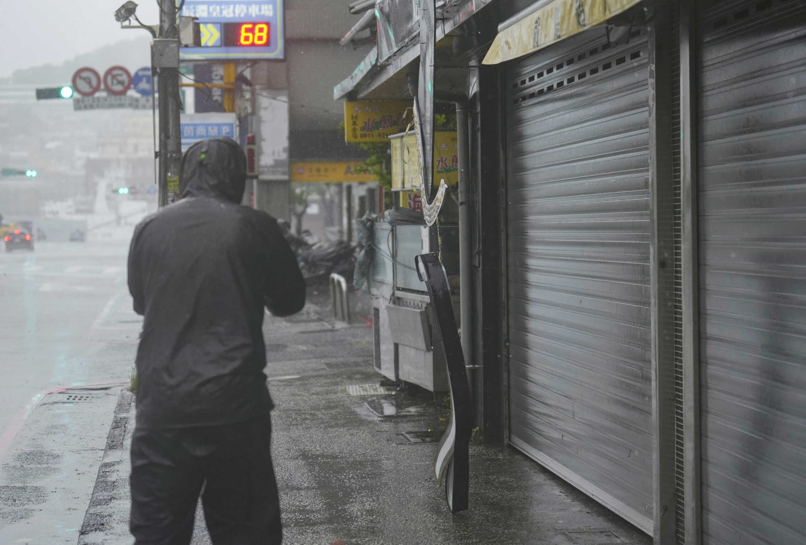 A person walks past a fallen light sign as Typhoon Kong-rey approaches in Keelung, Taiwan October 31, 2024. REUTERS