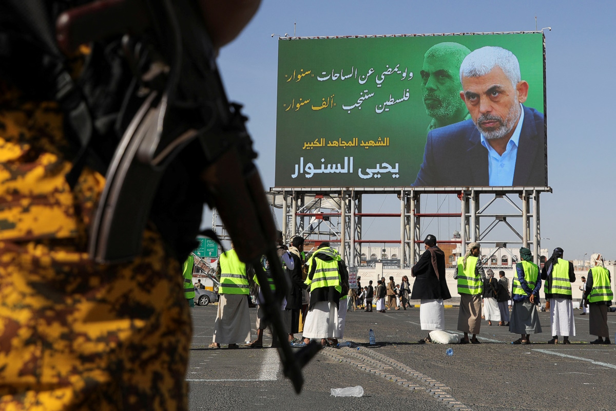 A member of the Houthi security forces stands guard in front of the billboard showing late Hamas leader Yahya Sinwar as protesters, mainly Houthi supporters, rally to show support to Lebanon's Hezbollah and Palestinians in the Gaza Strip, in Sanaa, Yemen October 18, 2024. REUTERS