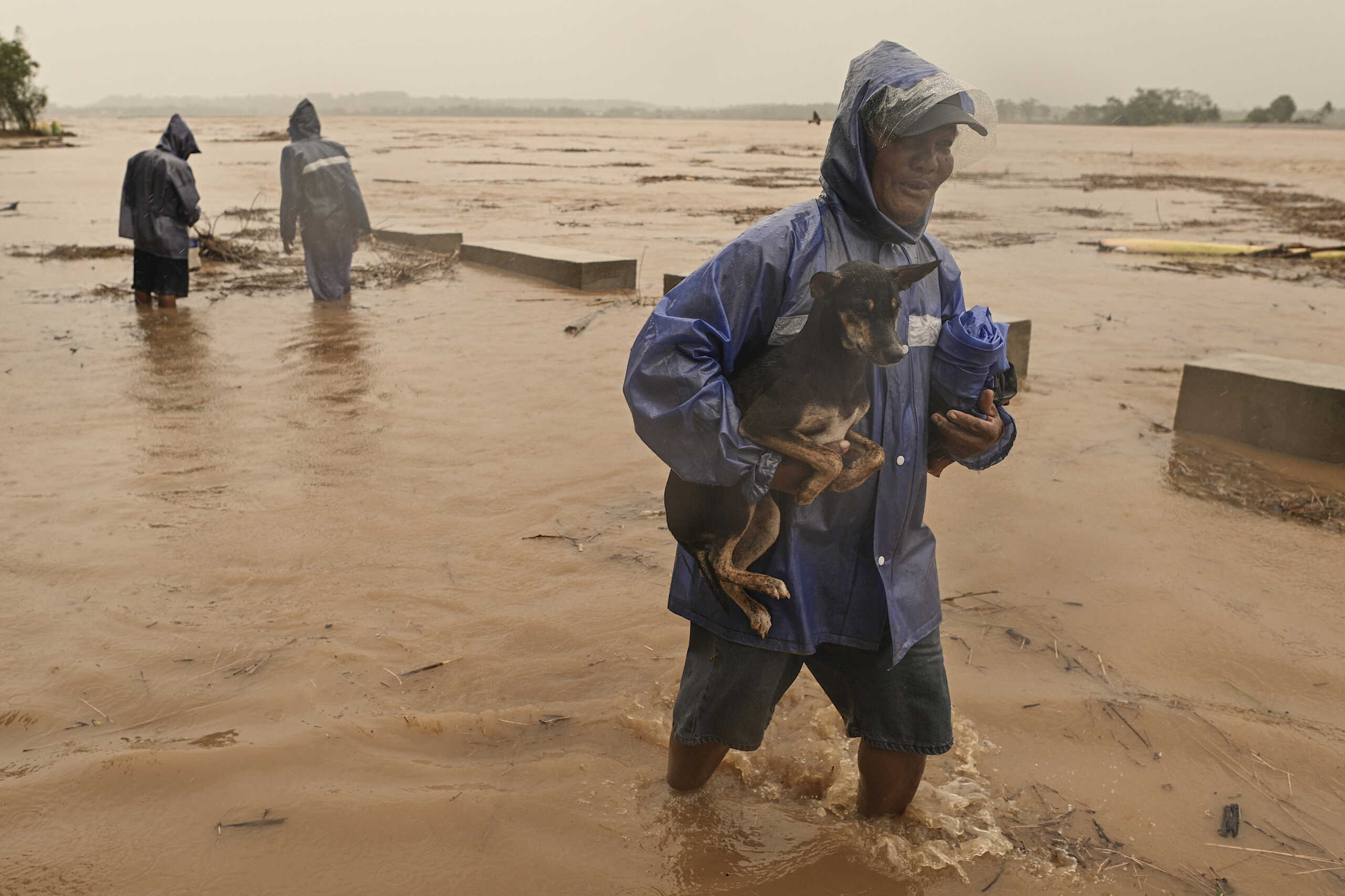 A resident carries his dog to safer grounds as they evacuate from their homes along a swollen river caused by heavy rains from Typhoon Toraji in Ilagan City, Isabela province, northern Philippines on Monday, Nov. 11, 2024. (AP Photo