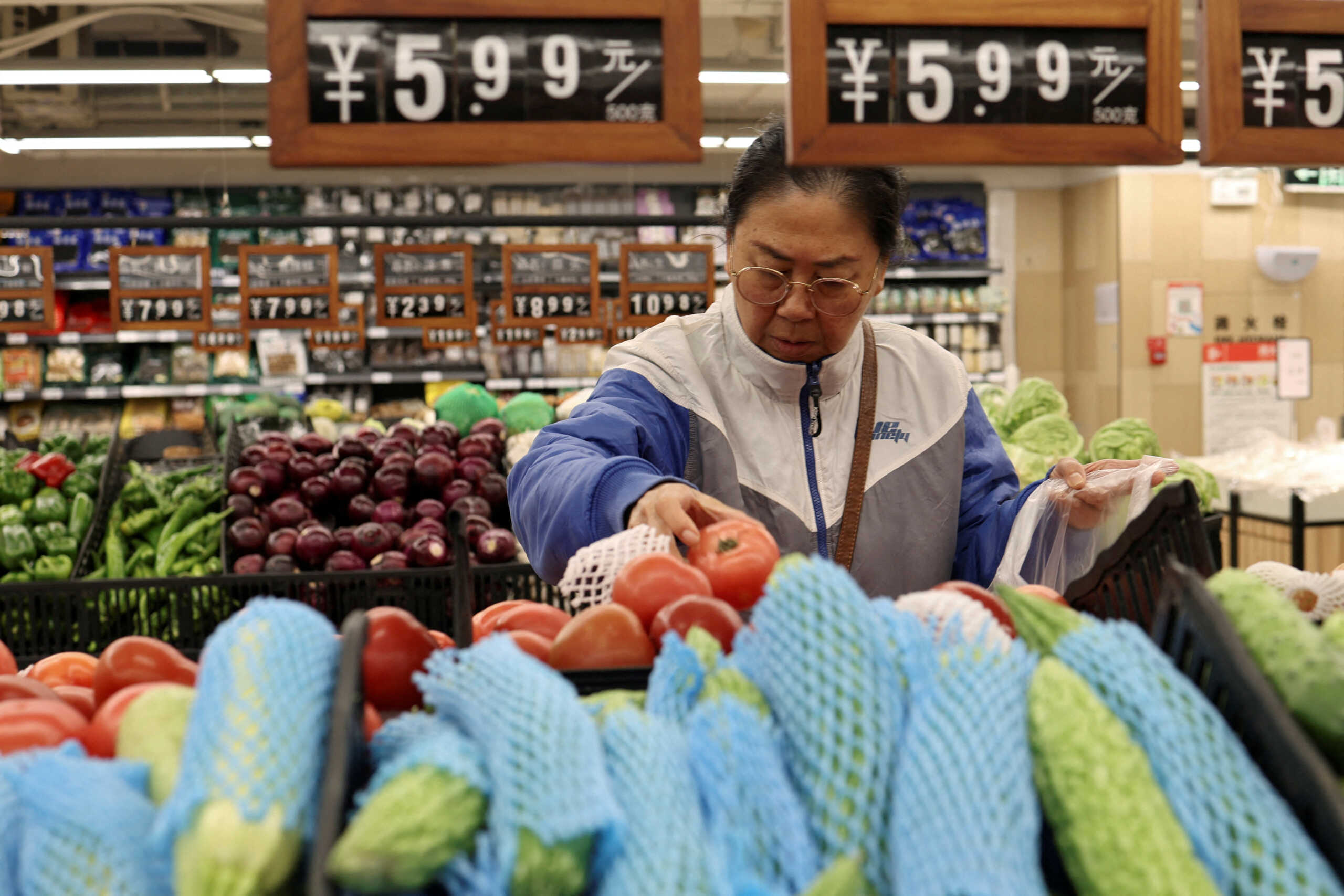 FILE PHOTO: A customer shops for tomatoes at the vegetable section of a supermarket in Beijing, China October 17, 2024. REUTERS