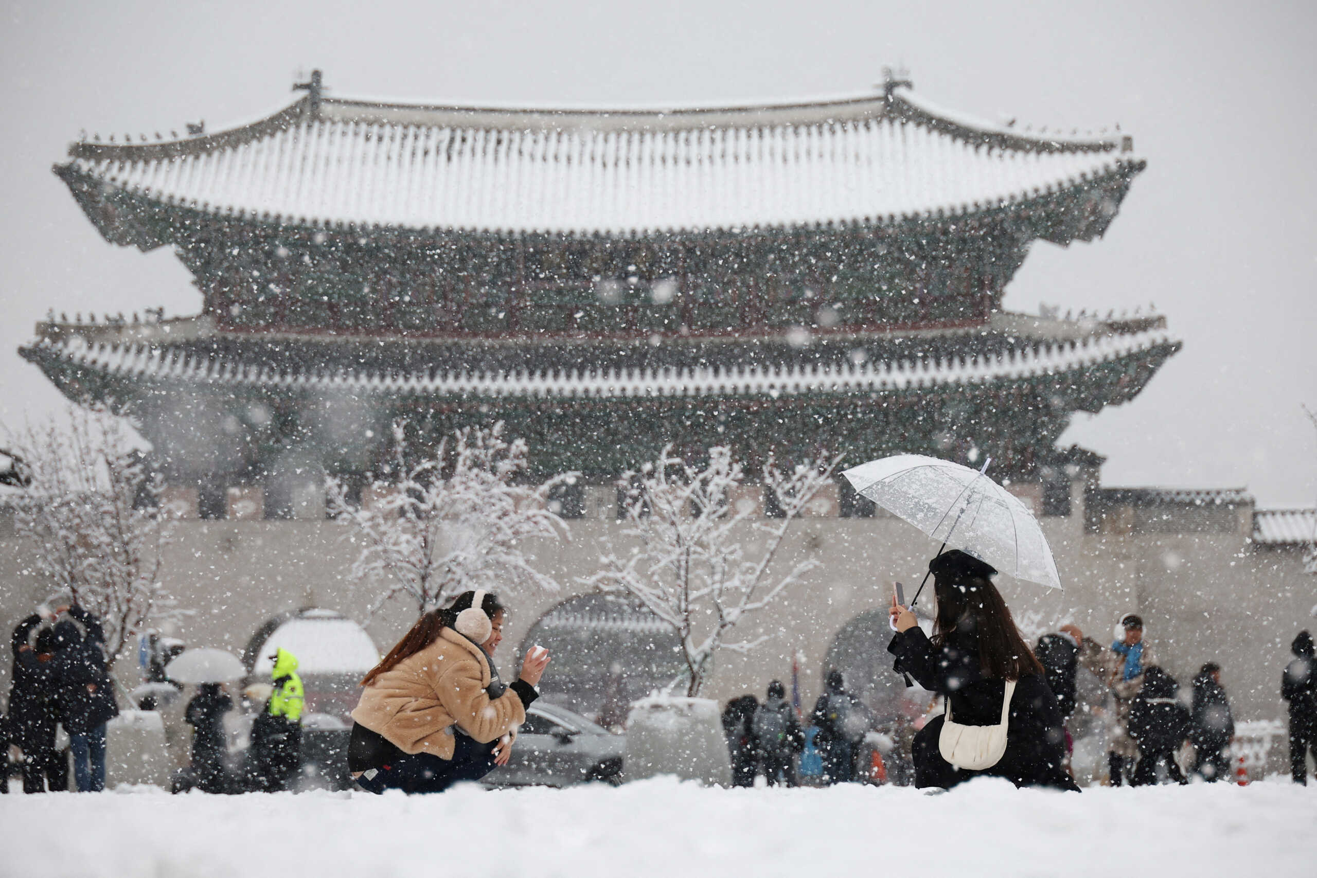 A woman takes a photographs of her friend during heavy snow fall in central Seoul, South Korea, November 27, 2024.   REUTERS