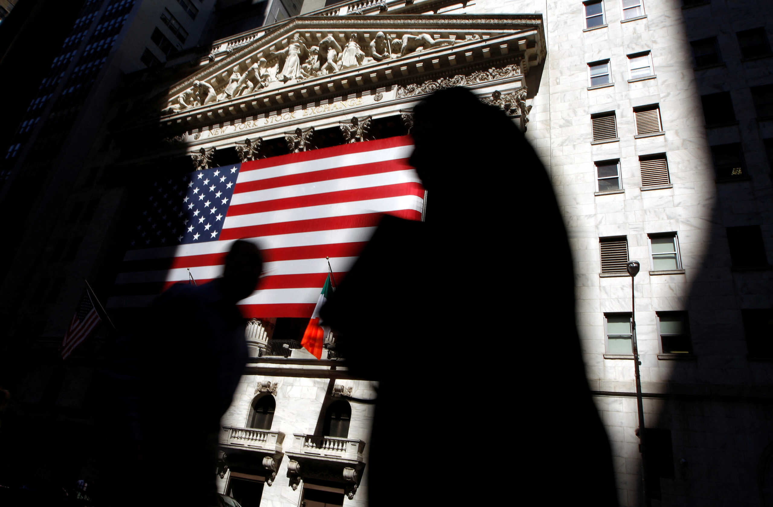 FILE PHOTO: The sun lights the exterior of the New York Stock Exchange, as people walk past on the shadowed street, July 16, 2008.  REUTERS