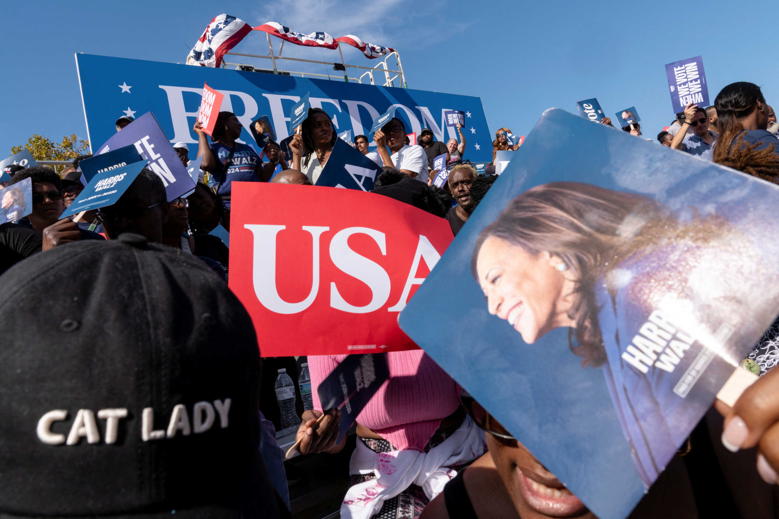 People use signs to shield themselves from the sun as they wait for the arrival of Democratic presidential nominee and U.S. Vice President Kamala Harris at a rally in Atlanta, Georgia, U.S., November 2, 2024.  REUTERS