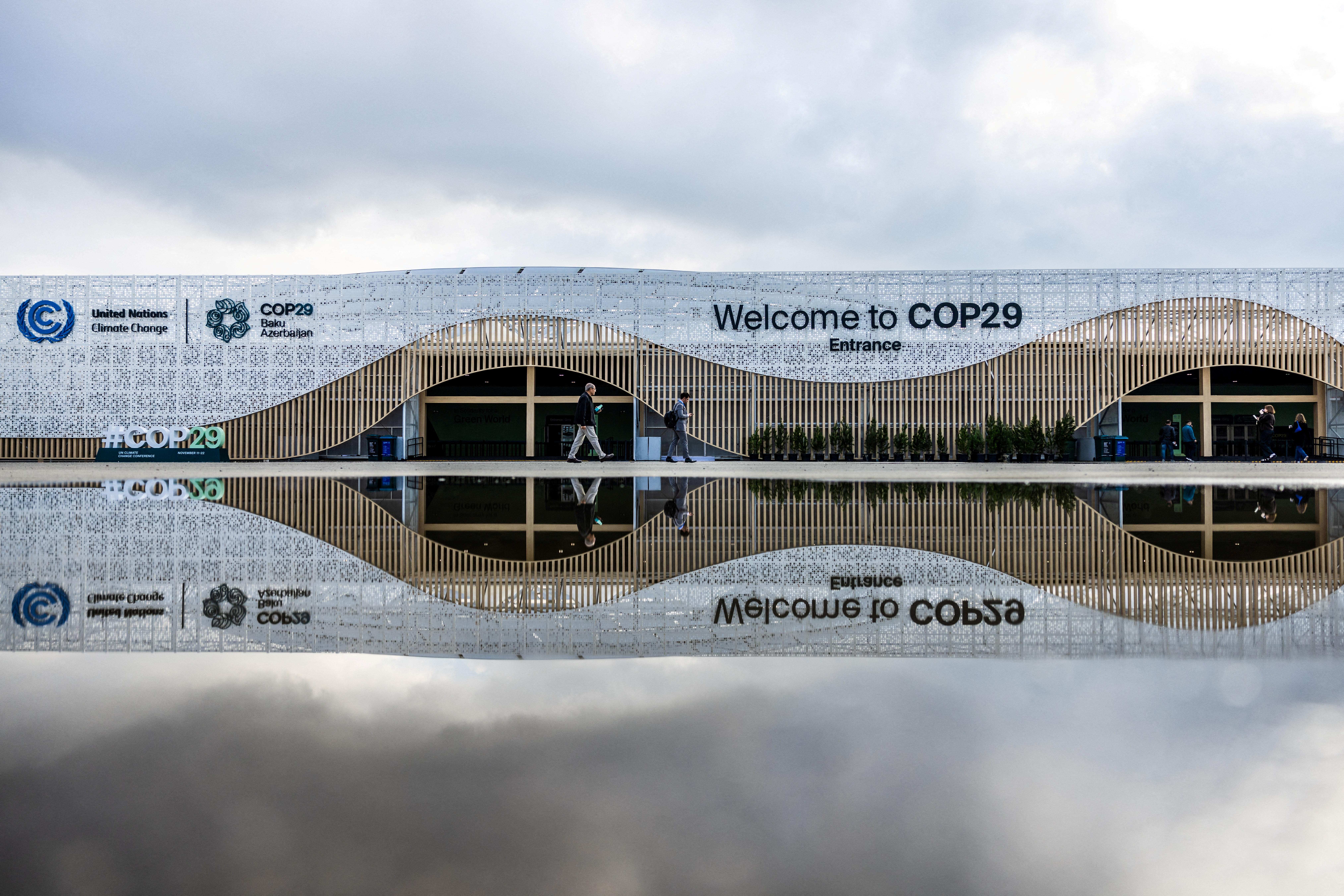 People walk near the entrance to the venue of the United Nations climate change conference, known as COP29, ahead of the summit beginning in Baku, Azerbaijan November 10, 2024. REUTERS