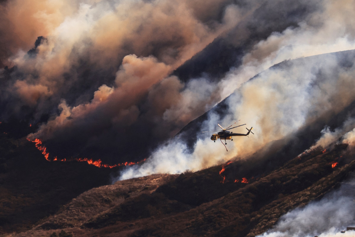 An helicopter flies as smoke billows from the Mountain Fire in Santa Paula, California, U.S., November 7, 2024. REUTERS