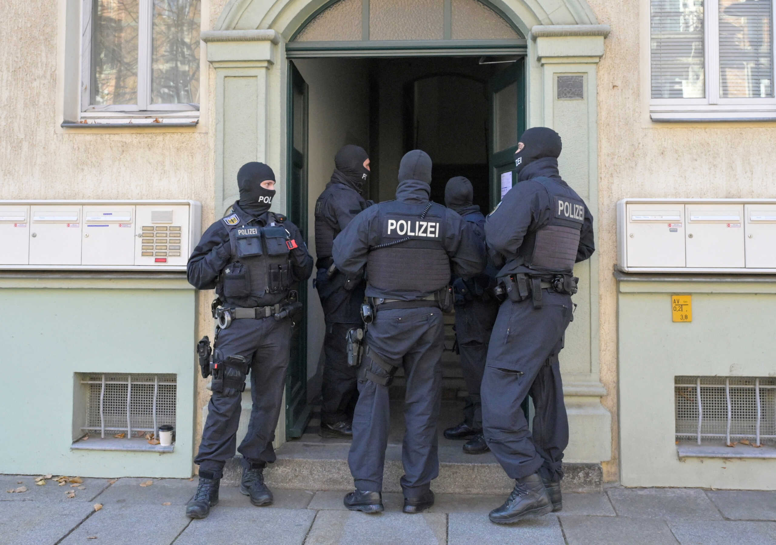 Masked German police officers guard a house after having arrested eight suspected members of a right-wing militant group driven by racist ideology and conspiracy theories who had been training in warfare for the downfall of the modern German state, in Dresden, Germany, November 5, 2024.   REUTERS