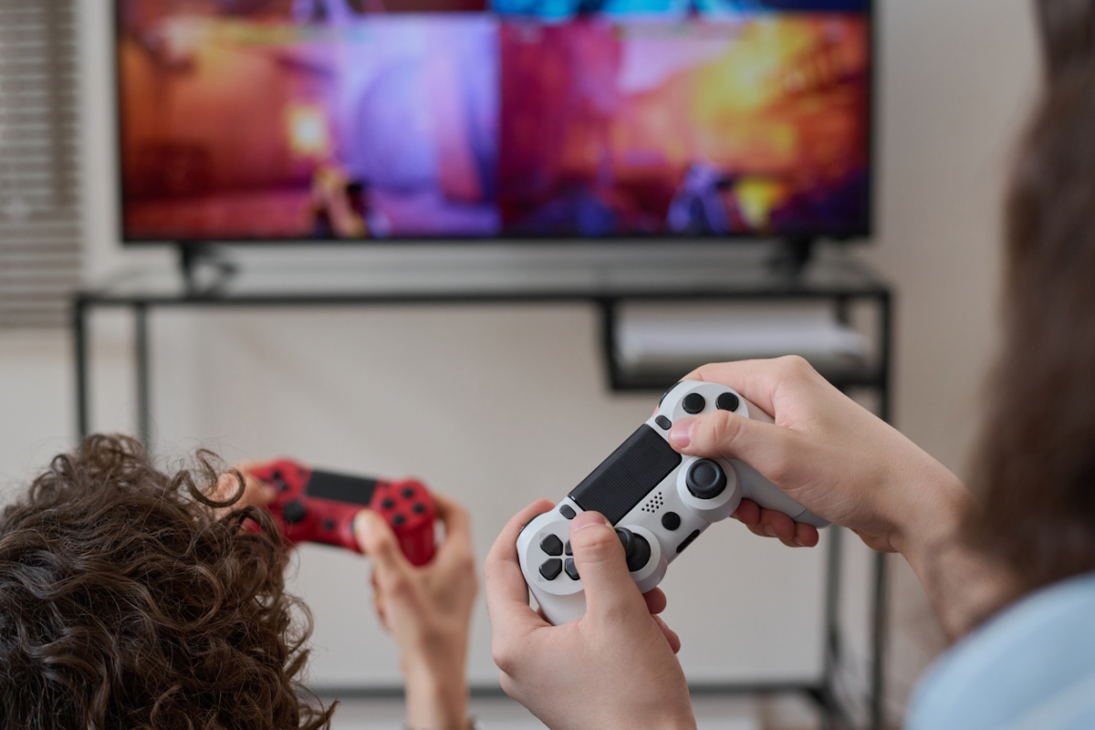 Rear view of family playing joysticks together while sitting at home