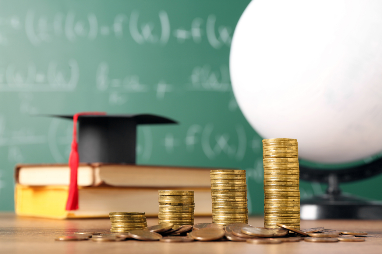 Scholarship concept. Graduation cap, books, globe and coins on wooden table