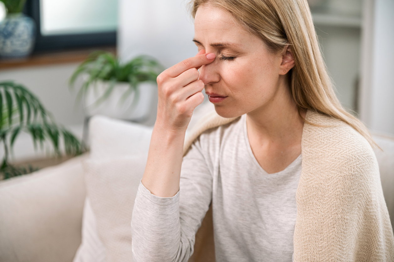 overworked woman with headache touching her nose bridge feeling tired and stress. sick young female with nasal discomfort suffering from sinusitis or respiratory infection