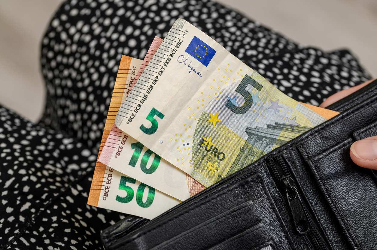 A woman holding a wallet with euro money sticking out