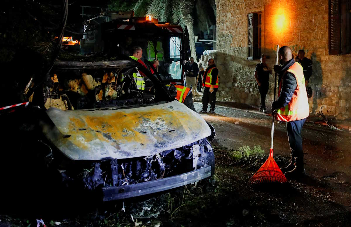 Emergency personnel work next to a destroyed vehicle at the site where a projectile fell after Israel's military reported projectiles crossing into Israel from Lebanon amid cross-border hostilities between Hezbollah and Israel, in Haifa, Israel, November 16, 2024. REUTERS