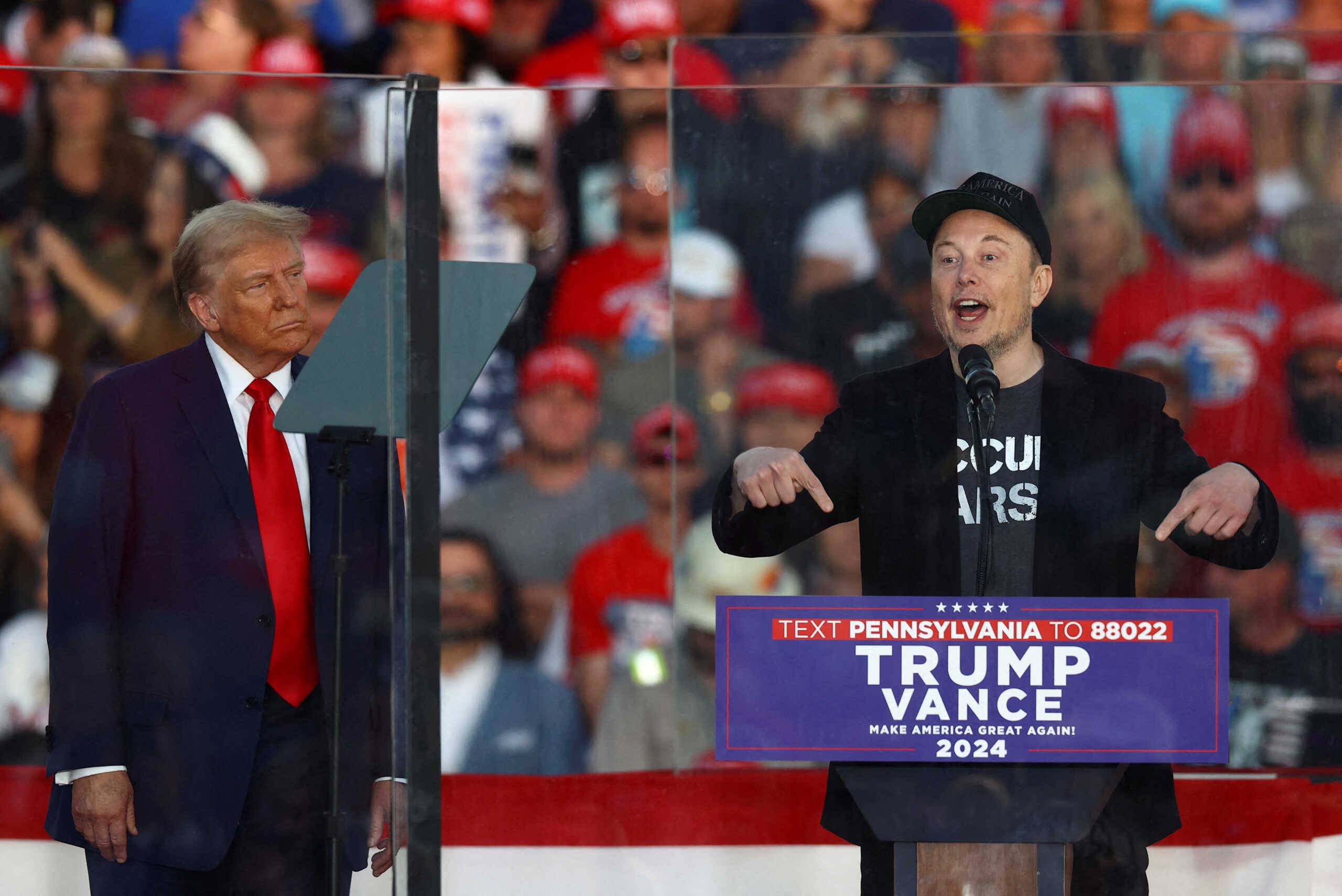 FILE PHOTO: Tesla CEO and X owner Elon Musk speaks as Republican presidential nominee and former U.S. president Donald Trump looks on during a rally at the site of the July assassination attempt against Trump, in Butler, Pennsylvania, U.S., October 5, 2024. REUTERS