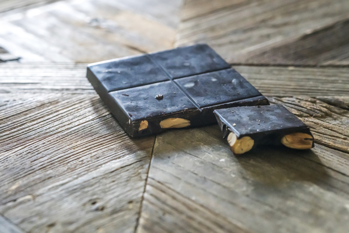 Homemade chocolate with almonds, broken into pieces, resting on a rustic wooden surface. (Felipe Rodriguez