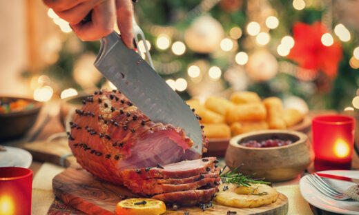 Woman carving glazed ham for holiday dinner