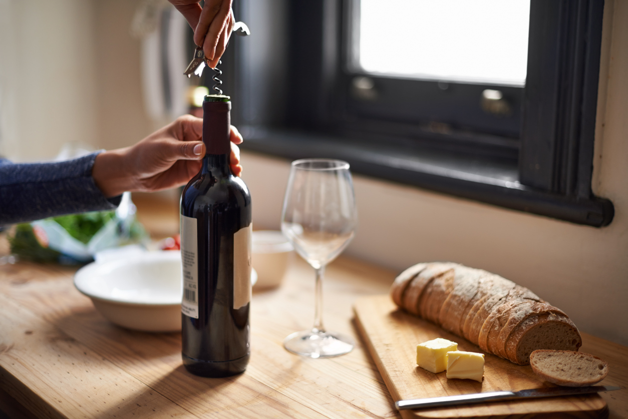 A young woman opening a bottle of wine with dinner