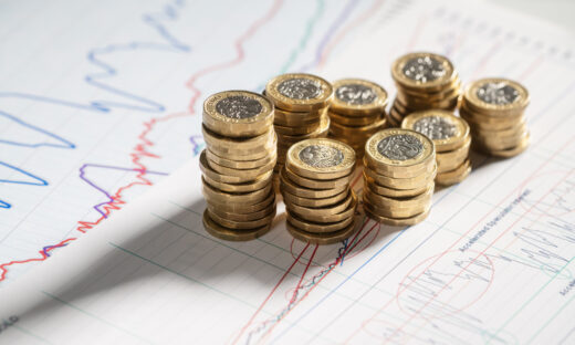 Stack of pound coins on financial graphs and figures