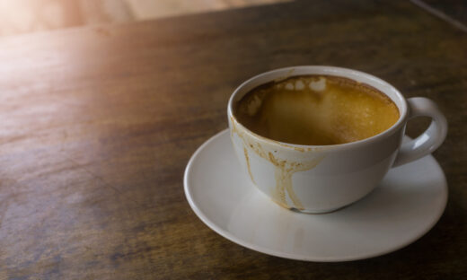 Coffee stains on a white coffee cup that placed on the brown wooden table in the morning, the sun shinning on a part of table