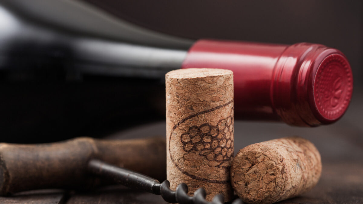 Wine corks with vintage corkscrew on wooden board background