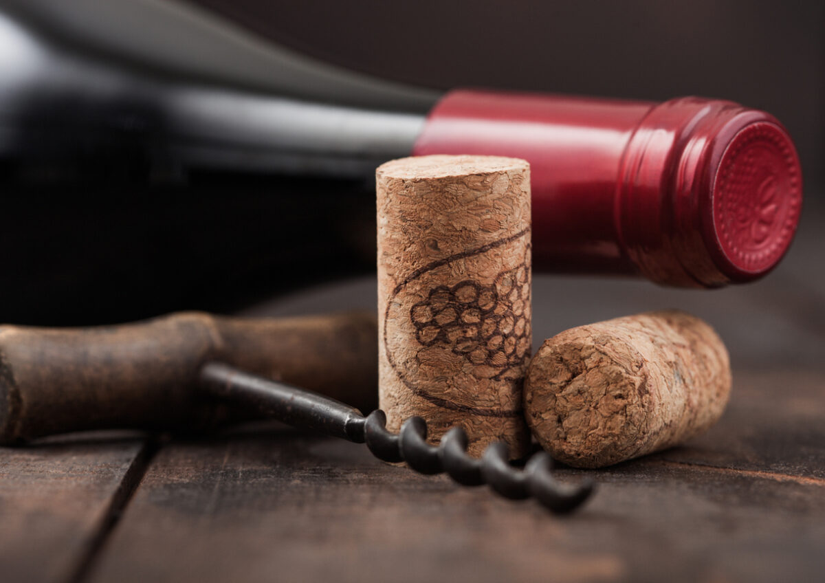 Wine corks with vintage corkscrew on wooden board background