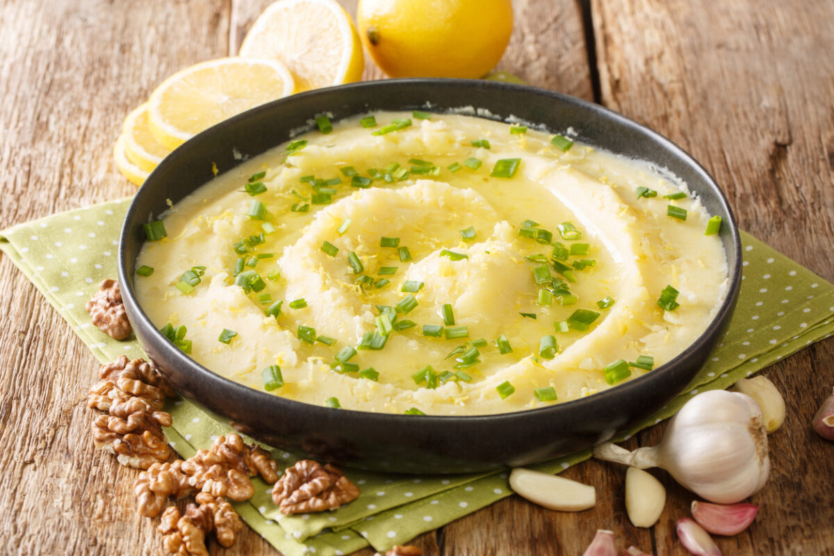 Homemade traditional appetizer Skordalia made of mashed potatoes with garlic, lemon, nuts and olive oil close-up on a plate on the table. horizontal