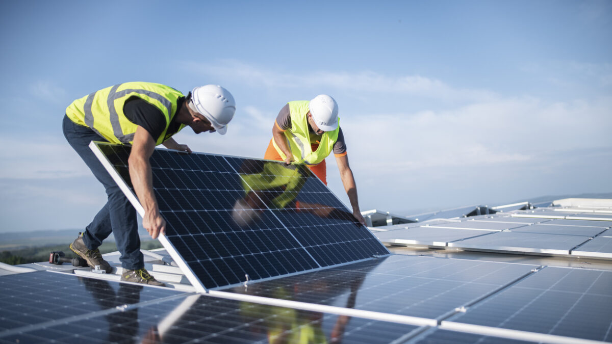 Team of two engineers installing solar panels on roof