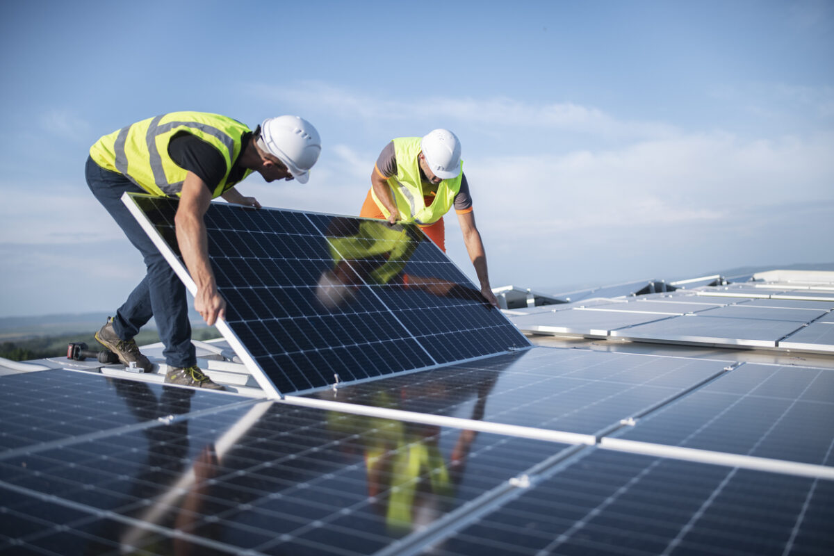 Team of two engineers installing solar panels on roof