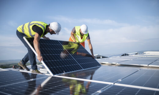 Team of two engineers installing solar panels on roof