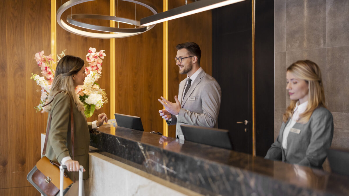 Male hotel receptionist assisting female guest