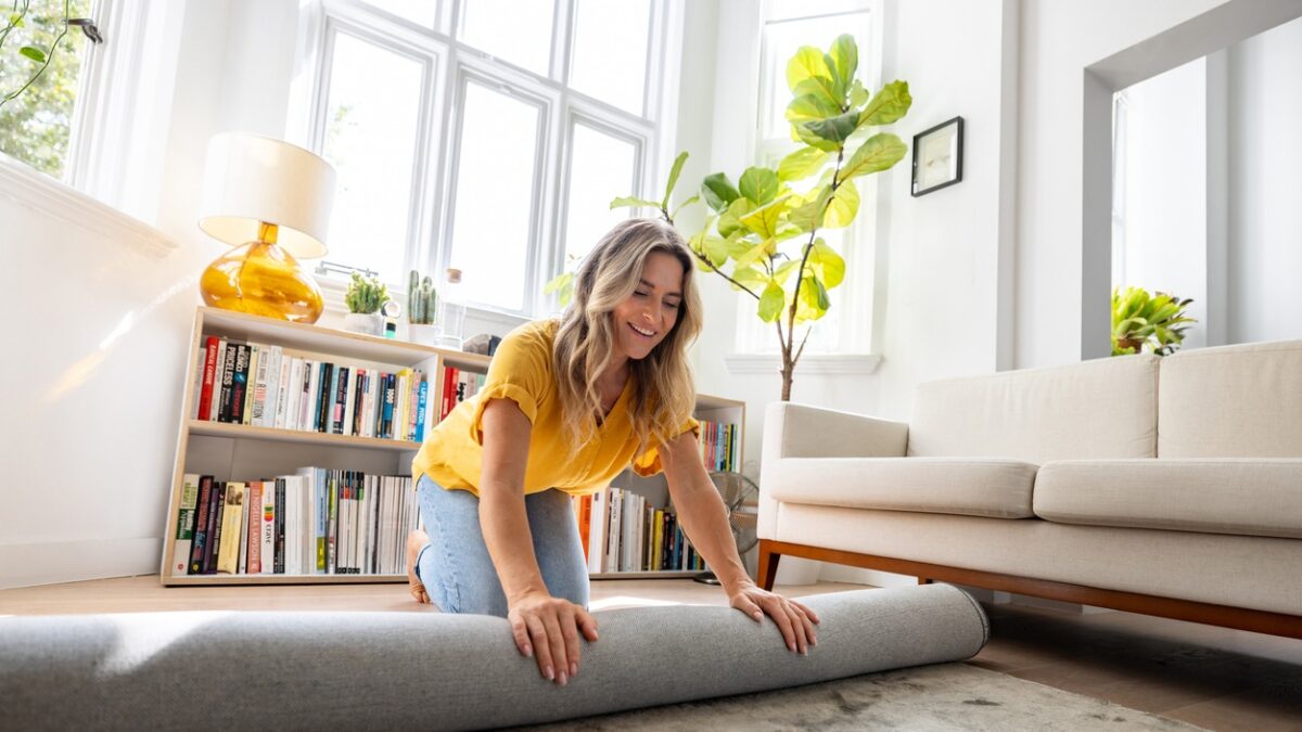 Woman moving house and unrolling a carpet