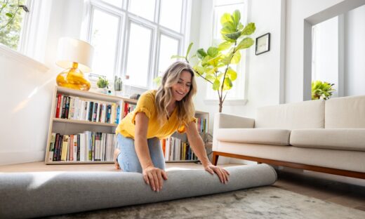 Woman moving house and unrolling a carpet