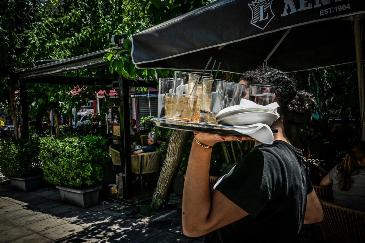 Σερβιτόρος κρατά γεμάτο δίσκο σε κατάστημα εστίασης