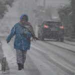 Μία γυναίκα περπατάει μέσα στα χιόνια