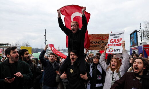 Ένας άνδρας έχει στους ώμους του μία γυναίκα που κρατάει μία τουρκική σημαία