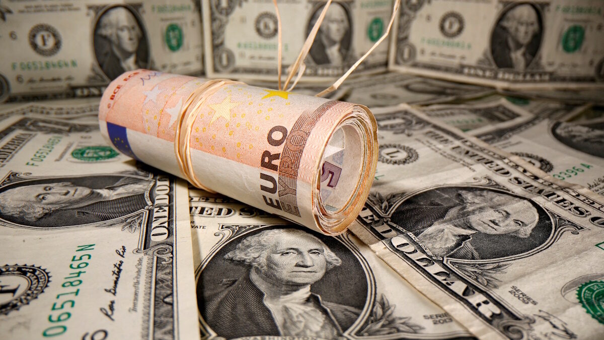 Rolled Euro banknotes are placed on U.S. Dollar banknotes