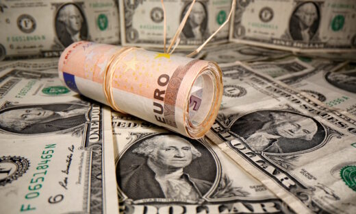 Rolled Euro banknotes are placed on U.S. Dollar banknotes