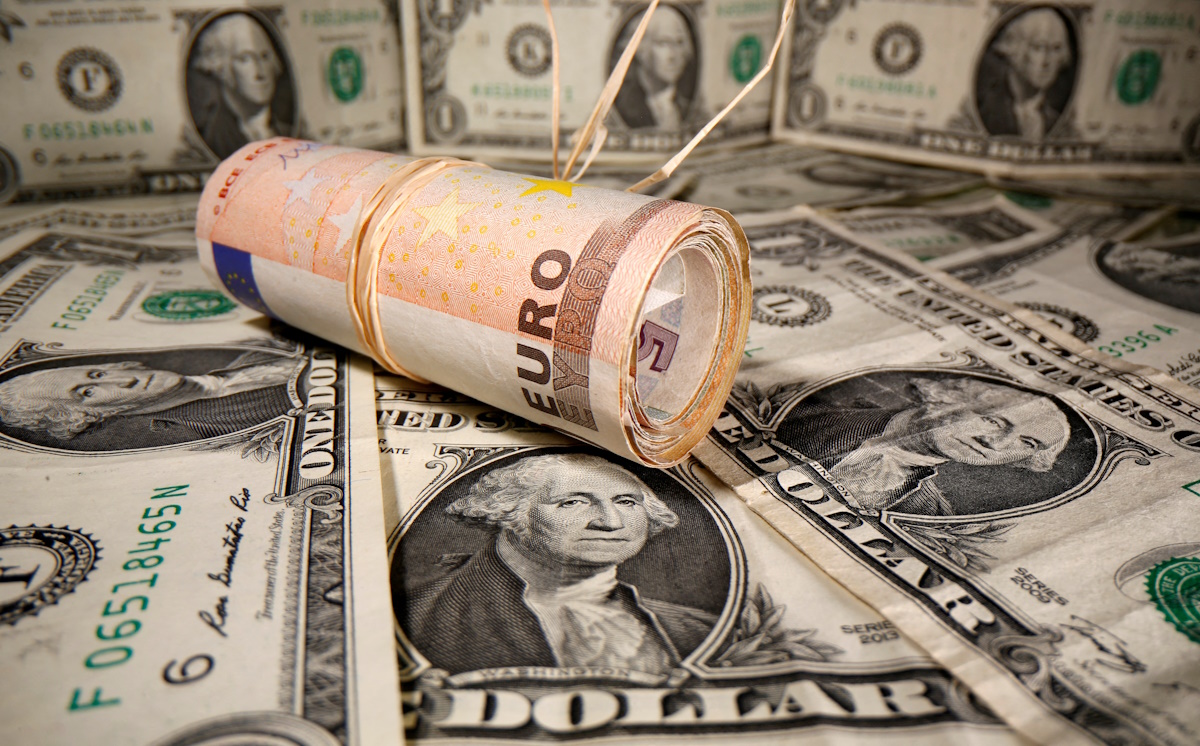 Rolled Euro banknotes are placed on U.S. Dollar banknotes