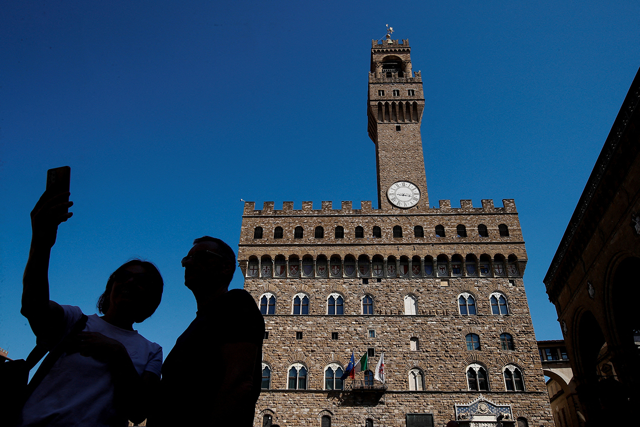 FILE PHOTO: People pose for selfies in front of the Palazzo Vecchio in Florence, Italy, April 13, 2024. REUTERS/Alessandro Garofalo/File Photo