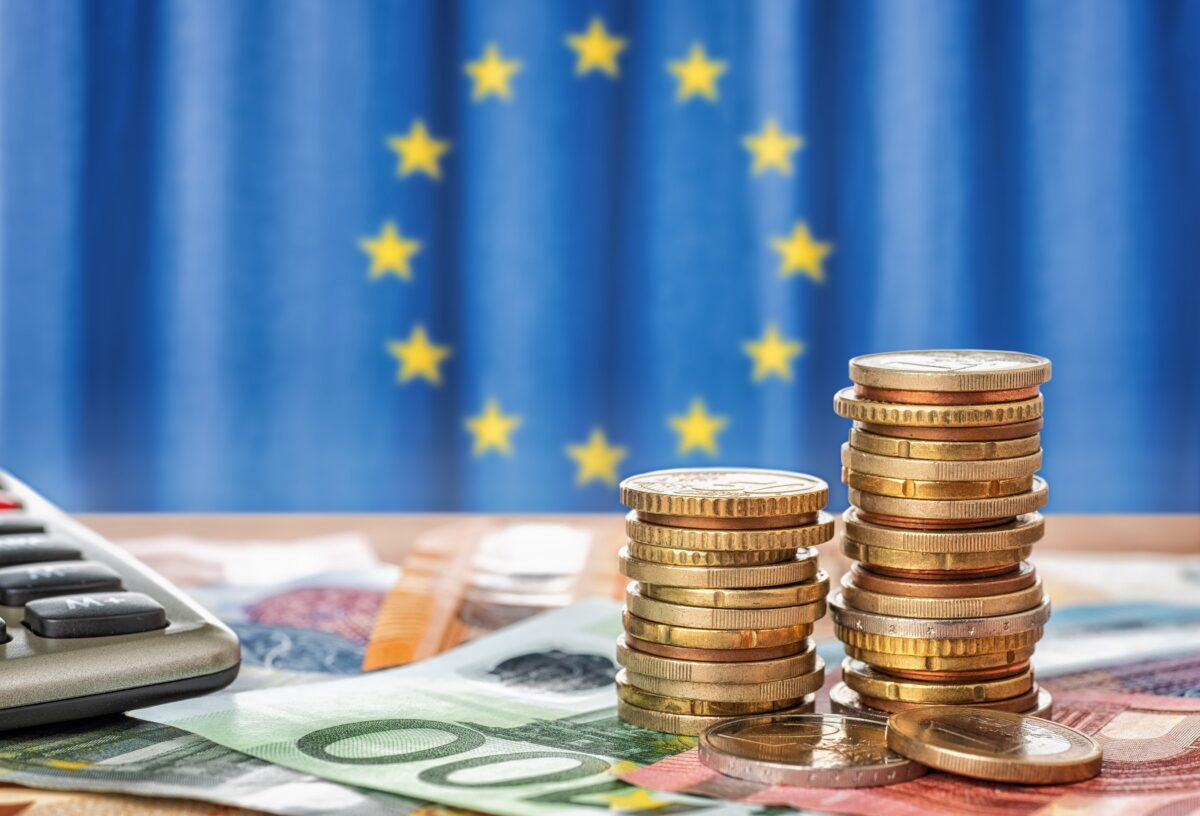 coins in front of the flag of the European Union