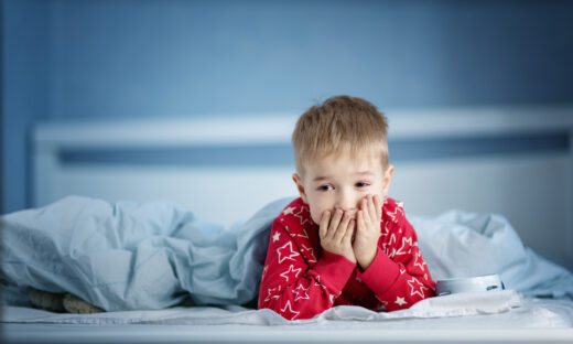 Sleepy boy lying in bed with blue beddings. Tired child in bedroom. Little kid lying awake in red pajamas with toothacheSleepy boy lying in bed with blue beddings. Tired child in bedroom sleeping. Little kid lying asleep in red pajamas with alarm clock